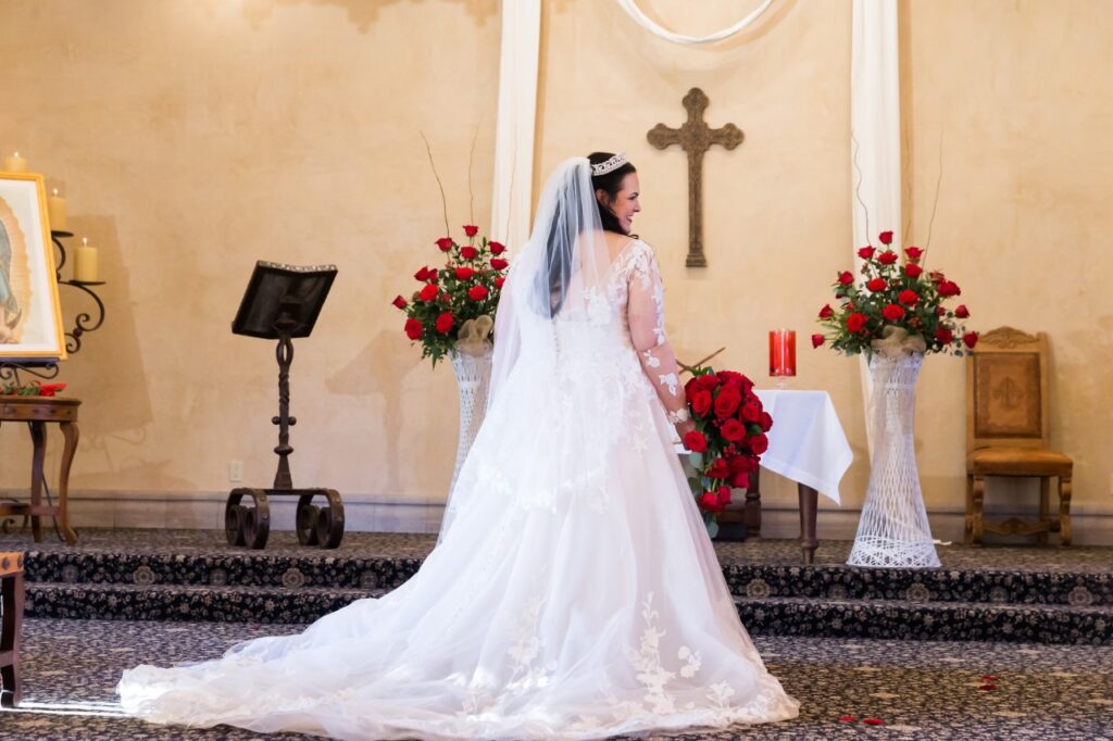 mid size bride wearing long sleeve lace wedding dress holding red rose bouquet arizona