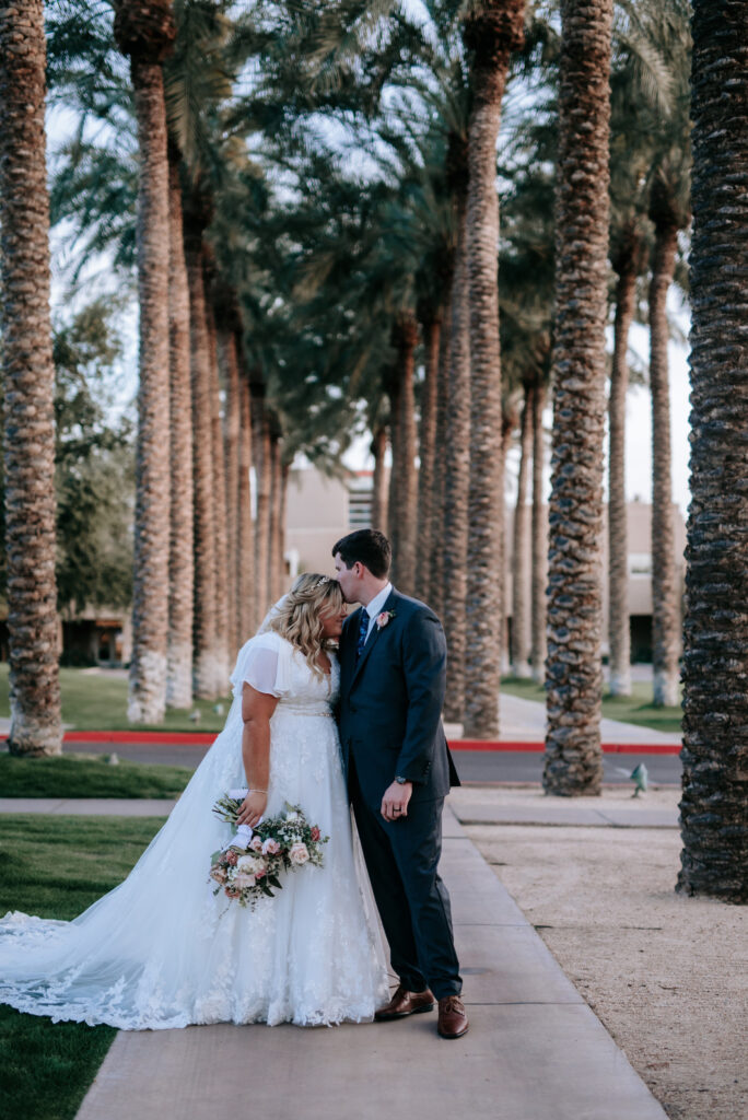 bride wearing modest wedding dress with groom in tux on grass in mesa arizona