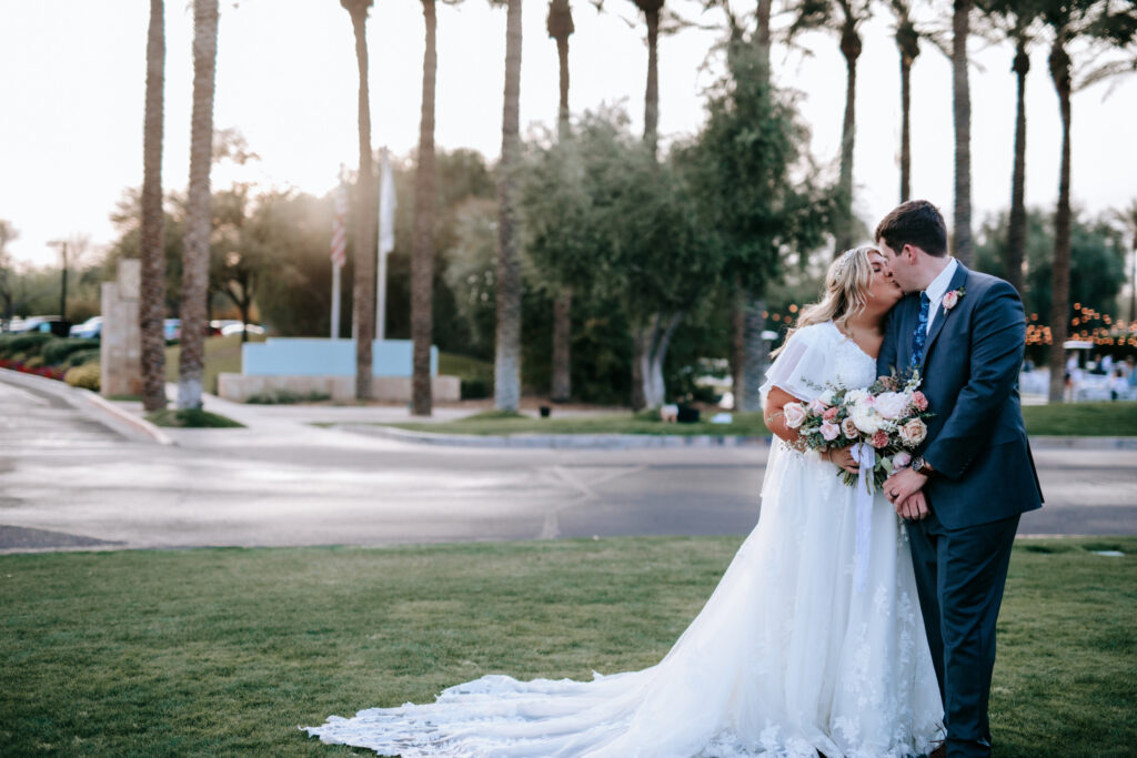 bride wearing modest wedding dress with groom in tux on grass in mesa arizona