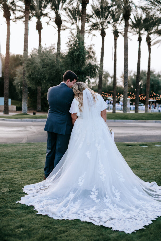 bride wearing modest wedding dress with groom in tux on grass in mesa arizona