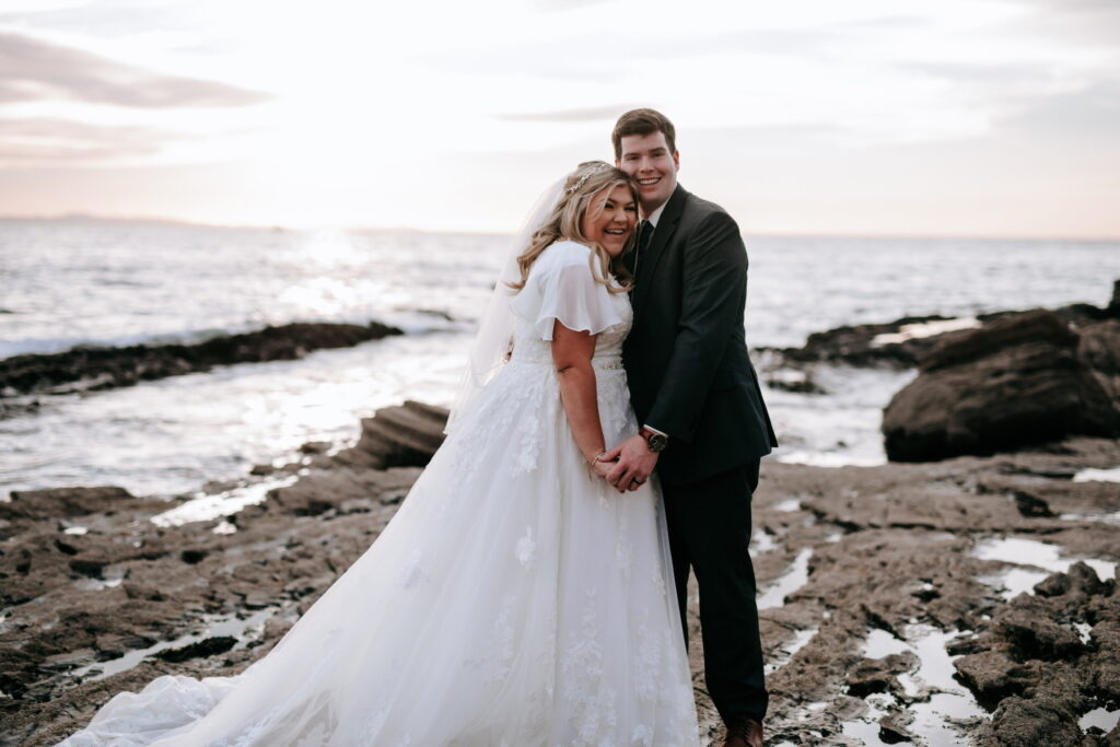 bride wearing modest wedding dress on beach with groom