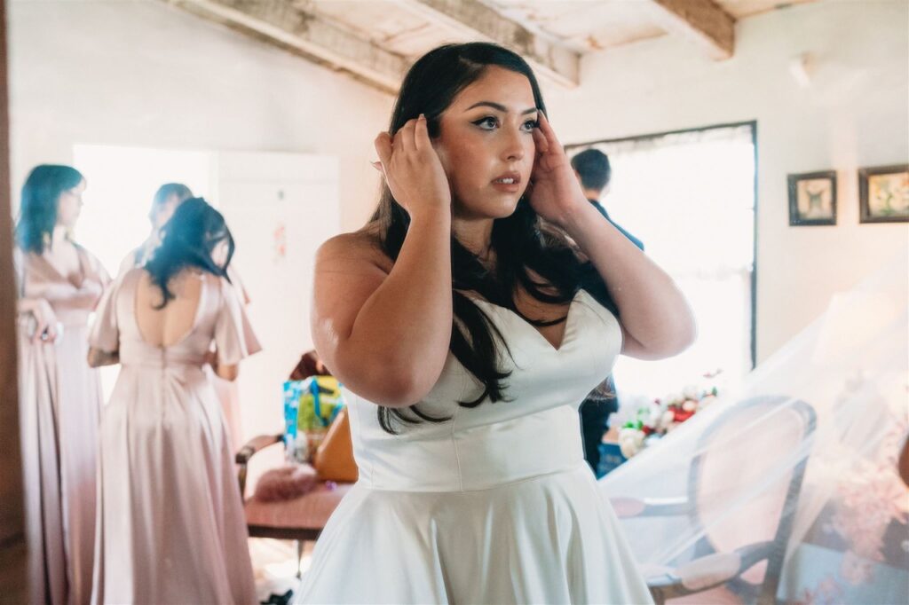 bride wearing satin ballgown wedding dress with red lace edge veil