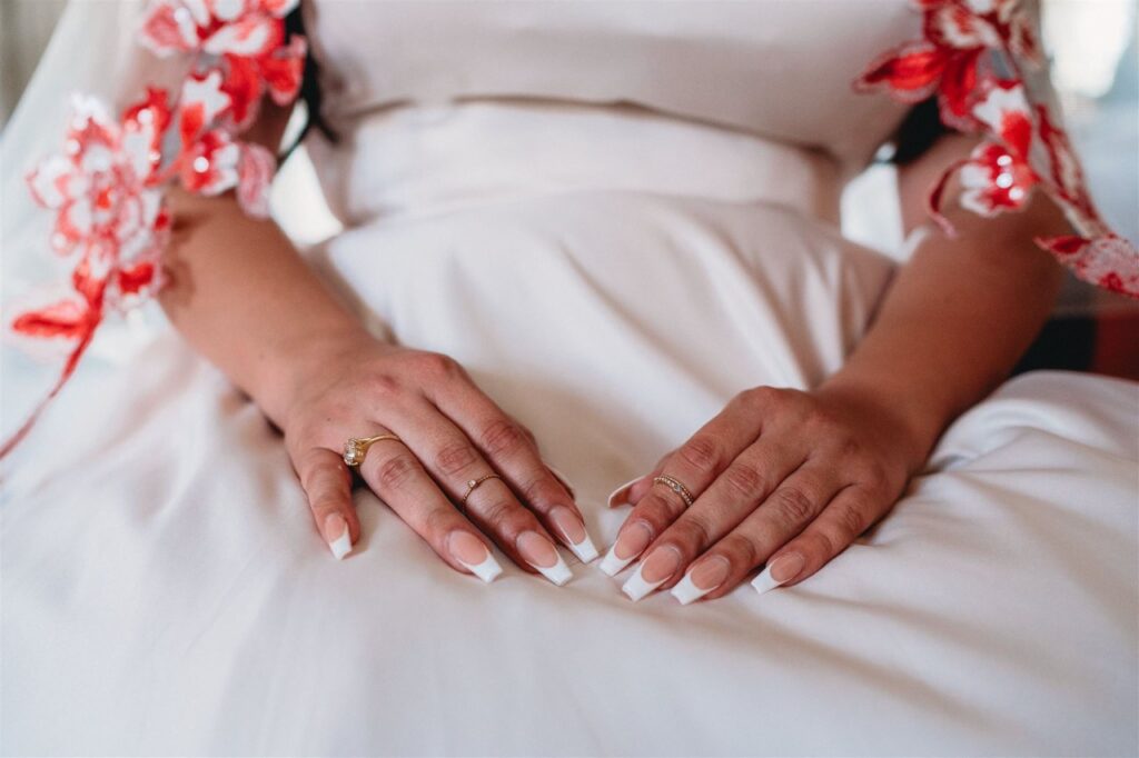 bride wearing satin ballgown wedding dress with red lace edge veil