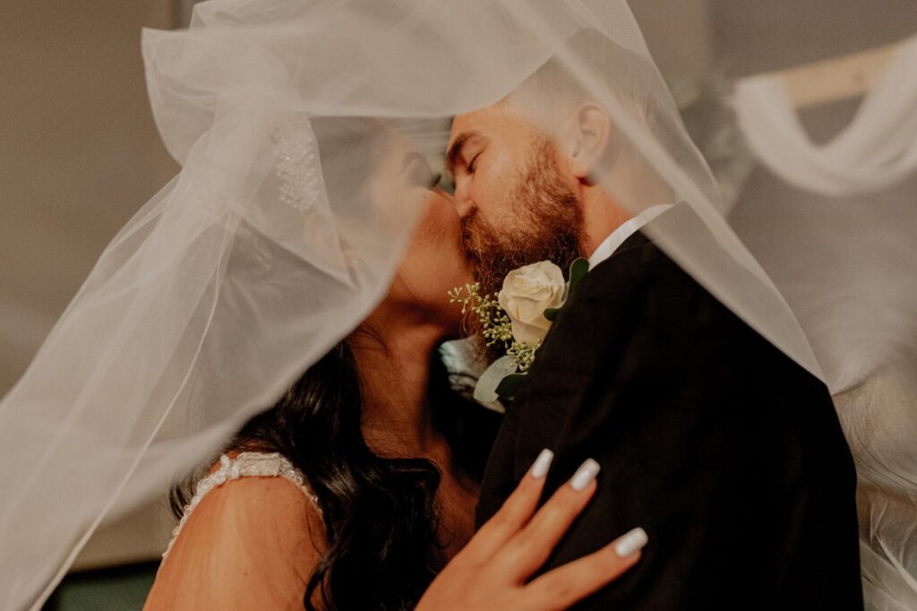 bride and groom kissing under veil