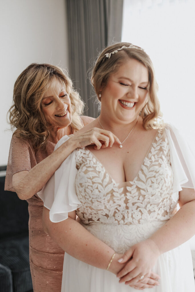 woman putting necklace on plus size bride