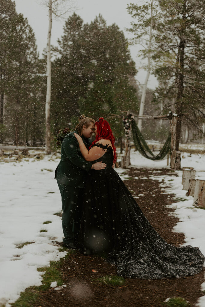groom and plus size bride wearing black wedding dress in snow in northern arizona winter wedding