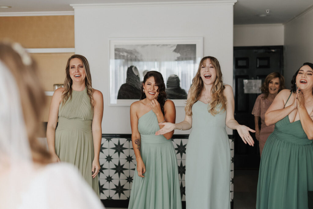bridesmaids in green dresses looking at bride