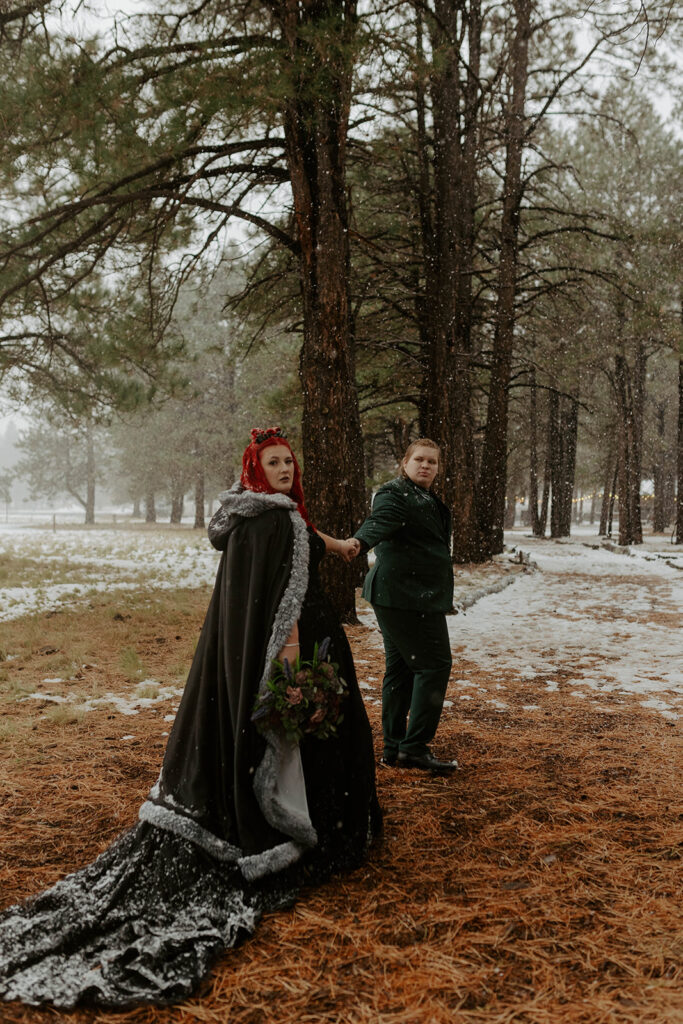 groom and plus size bride wearing black wedding dress in snow in northern arizona winter wedding