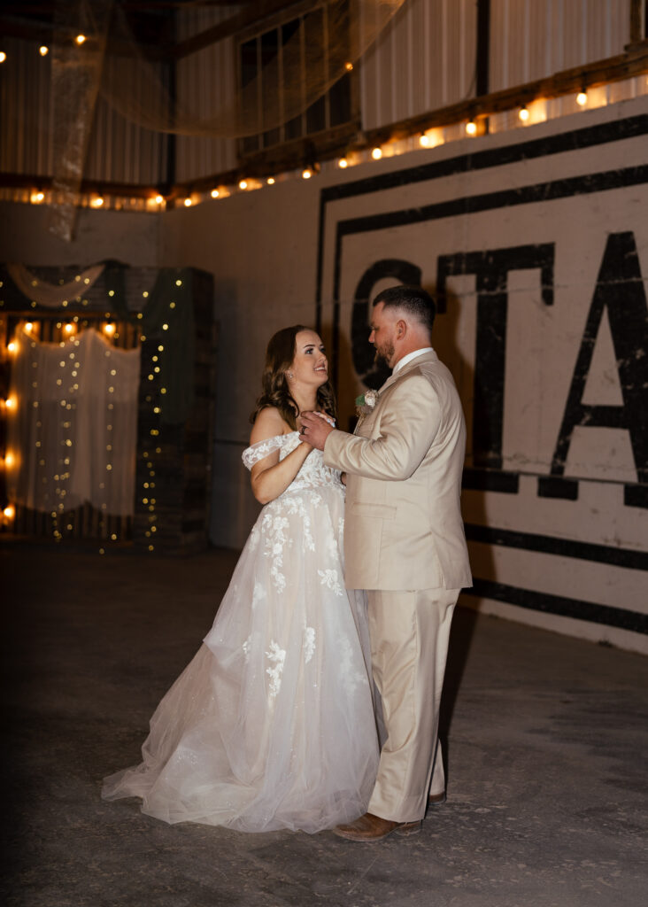 bride in aline wedding with lace tulle groom in tan suit dancing
