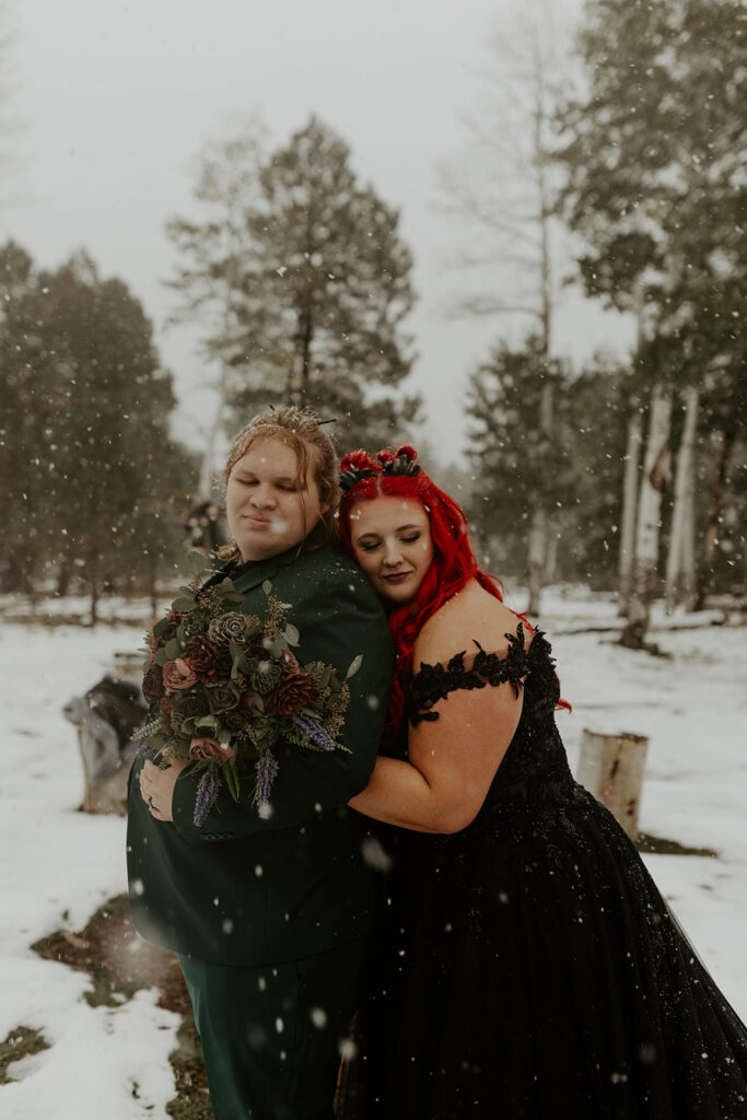groom and plus size bride wearing black wedding dress in snow in northern arizona winter wedding