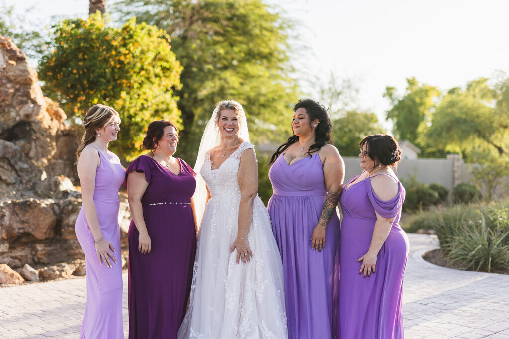 mature bride wearing neck traditional wedding dress at outdoor wedding in gilbert arizona from strut bridal salon with bridesmaid in purple dresses