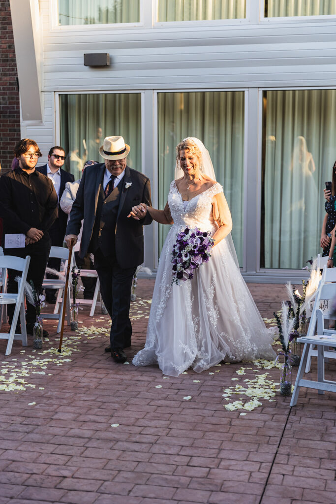 mature bride wearing neck traditional wedding dress at outdoor wedding in gilbert arizona from strut bridal salon walking down the aisle