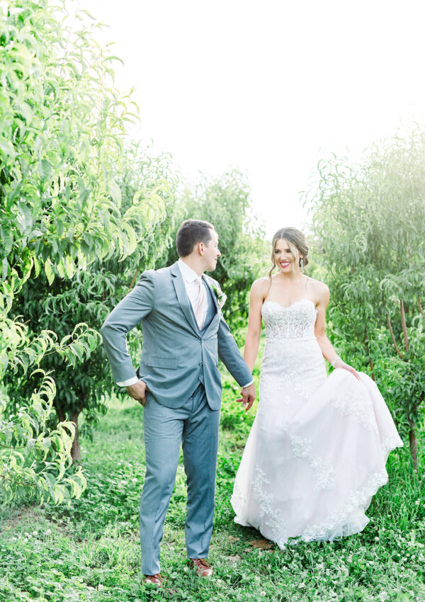 bride in wedding dress and groom in tux in green field