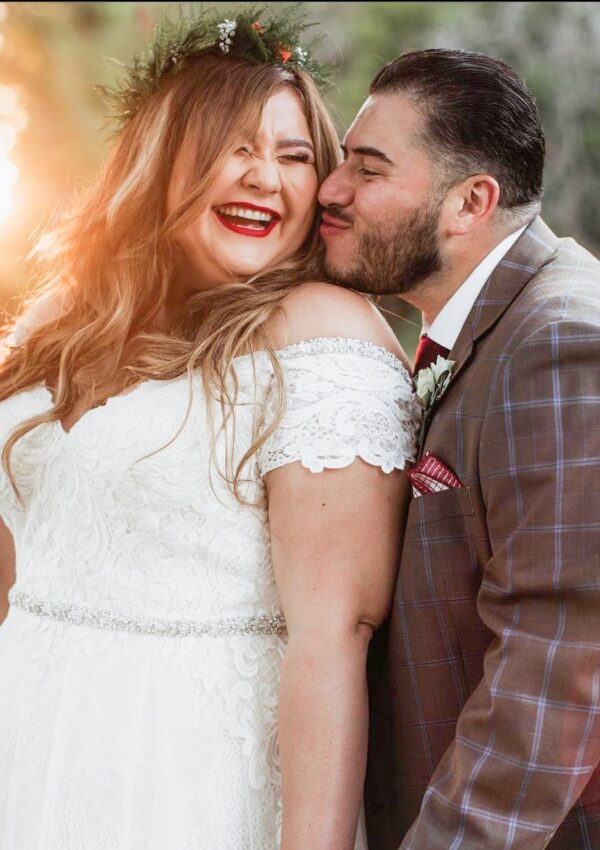bride wearing wedding dress with off the shoulder sleeve kissing groom