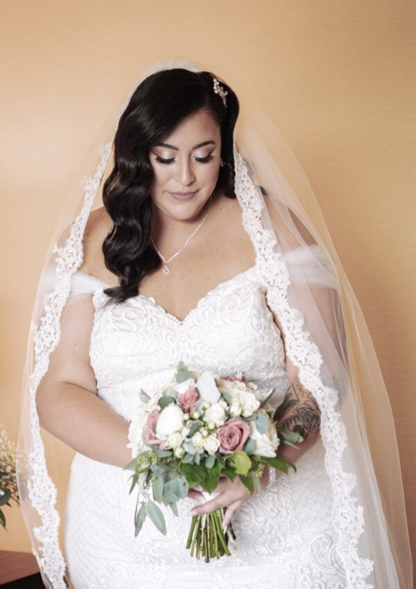 plus size bride with off the shoulder sleeves and lace veil