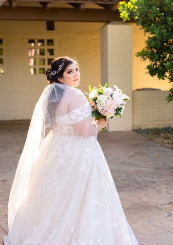 bride wearing off the shoulder lace ballgown holding flowers